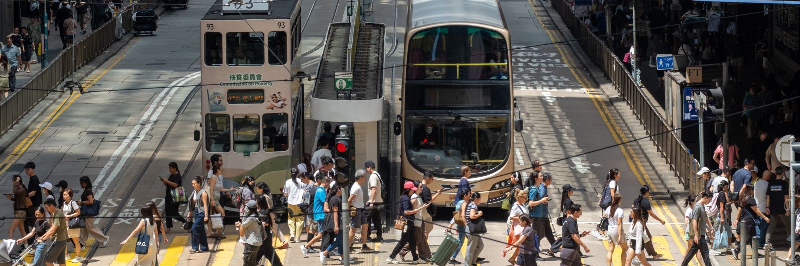 A busy Hong Kong street with trams and people crossing the road