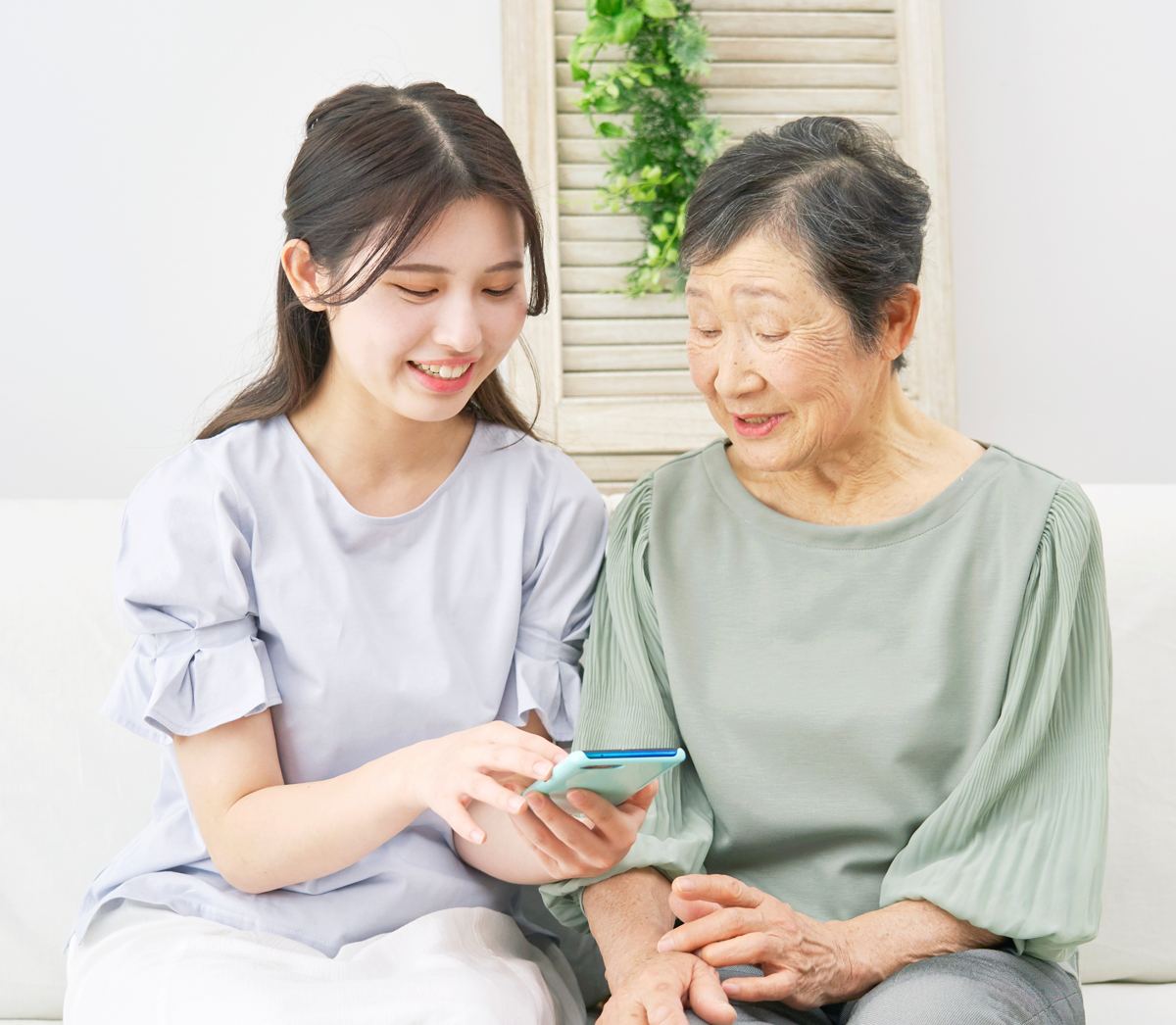 A young woman and an older woman looking at a phone together, smiling