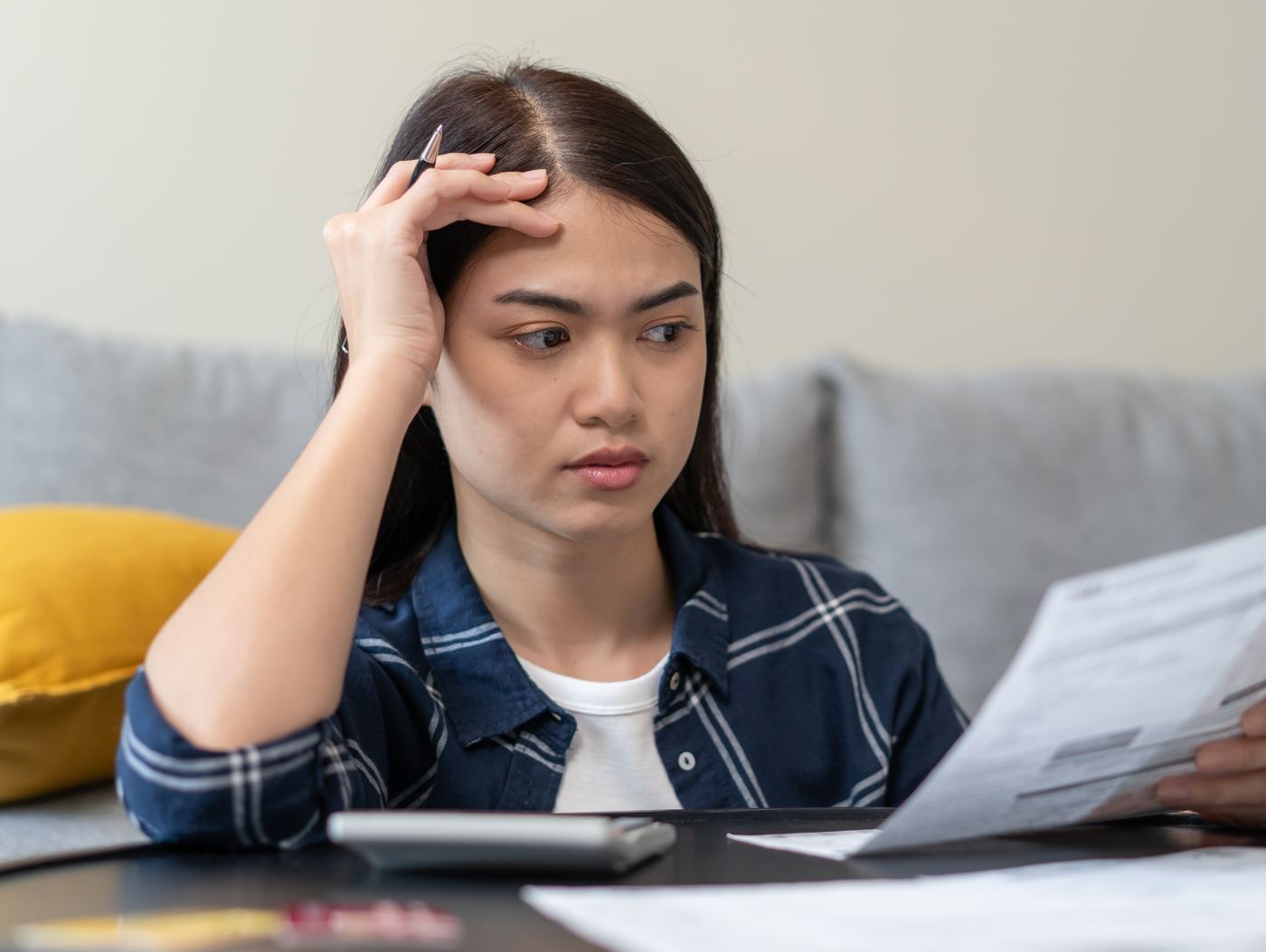 Woman on a sofa looking worried at a document